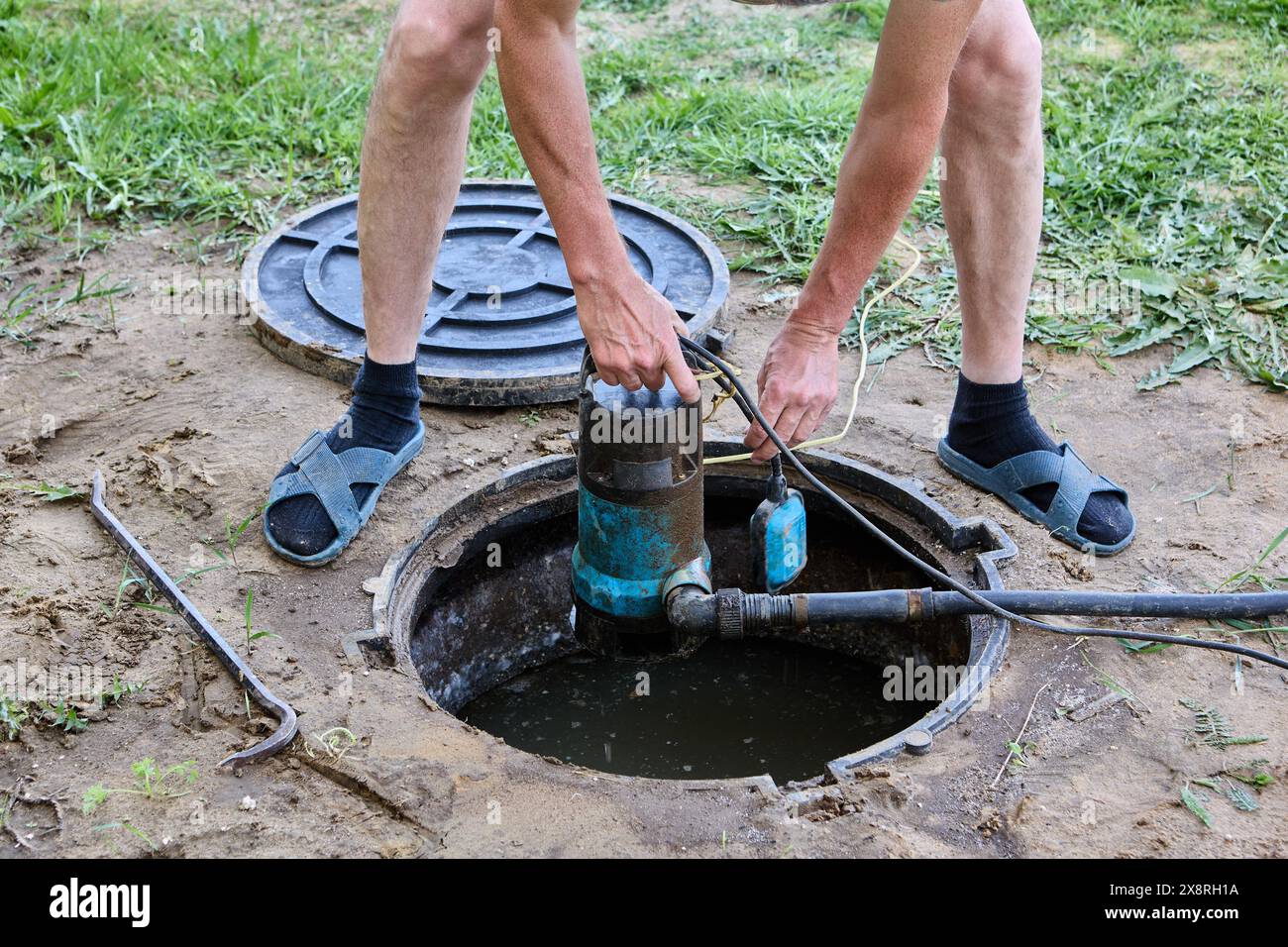 Le plombier submerge la pompe d'eaux usées dans l'effluent de fosse septique pour pomper les eaux usées avant l'entretien du réservoir. Banque D'Images