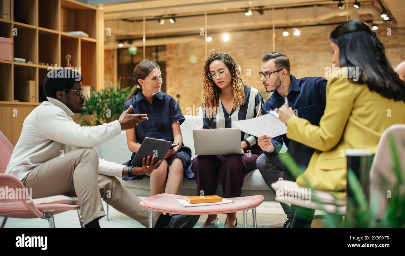 Groupe de personnes de différentes ethnies travaillant sur la résolution de problèmes à l'aide de Notes, d'un ordinateur portable et d'une tablette dans une salle de réunion au bureau. Les coéquipiers donnent un feedback constructif sur les projets d'eachother Banque D'Images