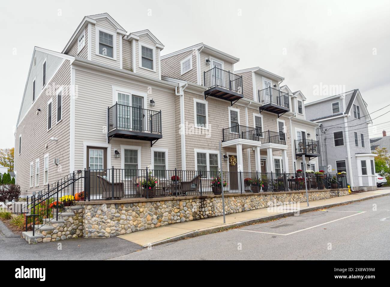 Nouvelles maisons en rangée avec un jardin clôturé le long d'une rue par un jour nuageux d'automne Banque D'Images