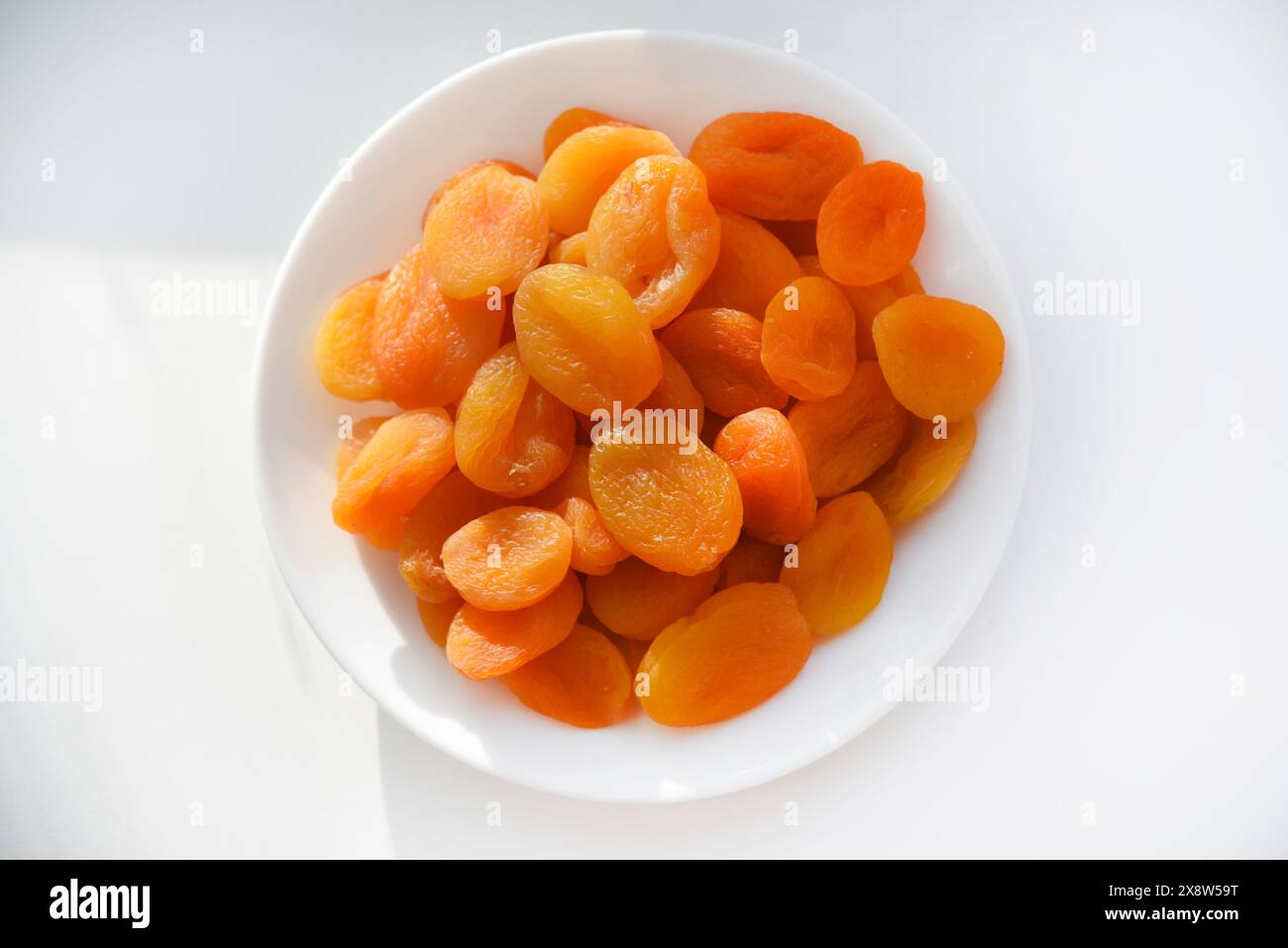 Fruits secs. Abricots séchés. Abricots séchés en gros plan sur une assiette blanche. Banque D'Images