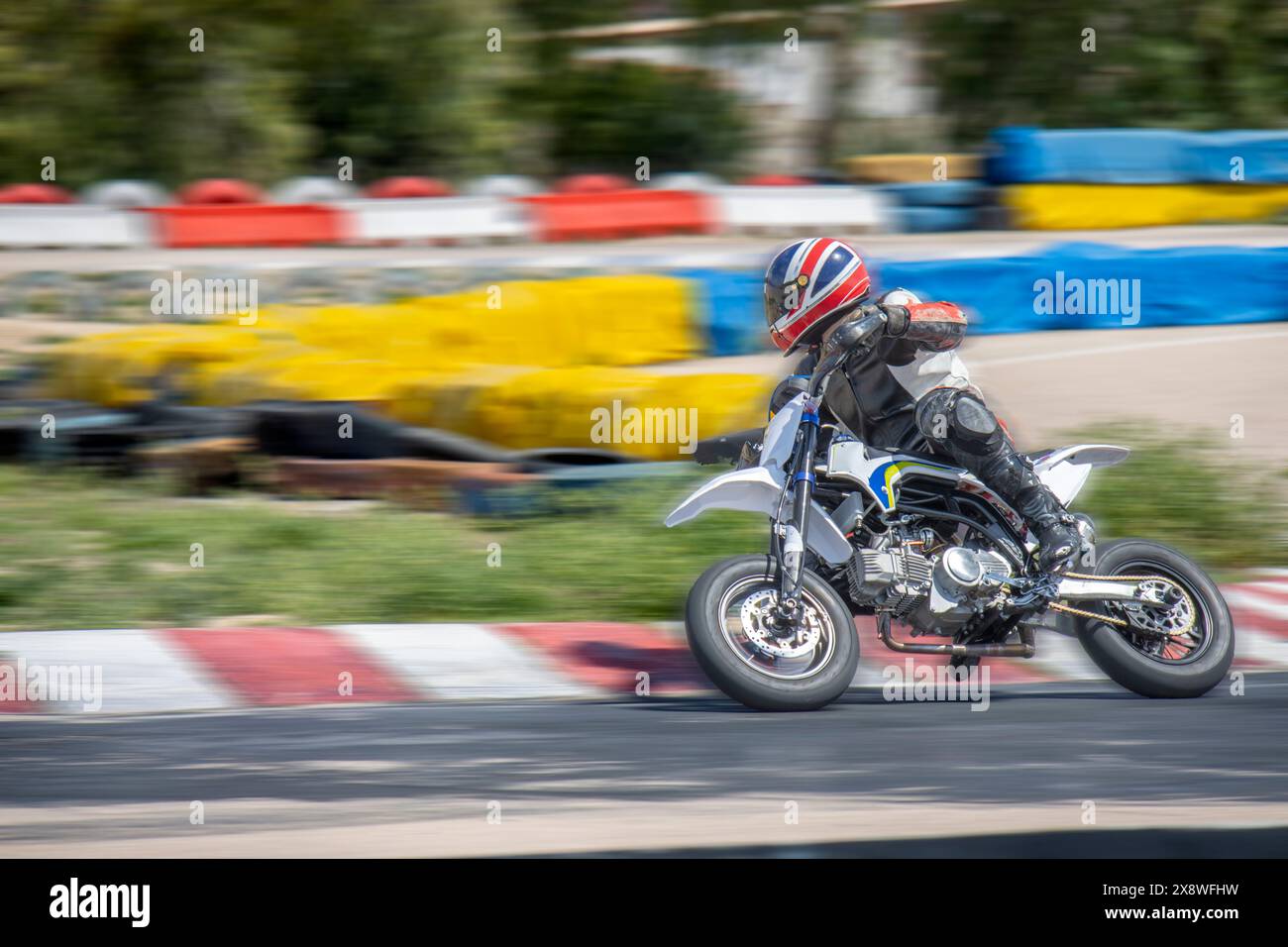 Le pilote de moto à pleine vitesse accélère sur une piste de course, capturé avec un flou de mouvement. Banque D'Images
