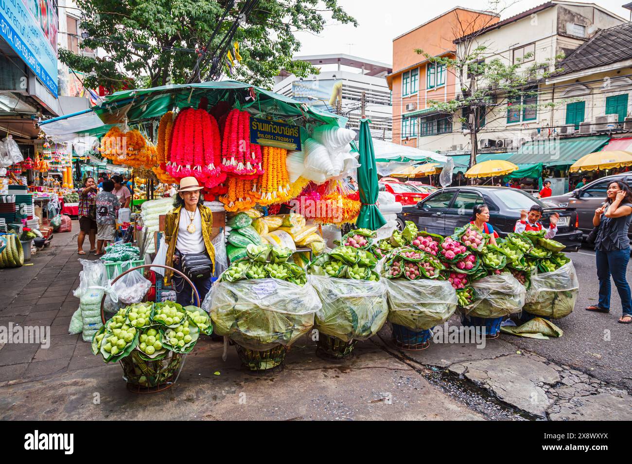 Stalle de bord de route et étallholder masculin vendant des fleurs colorées et des guirlandes à l'extérieur du marché aux fleurs en gros de Yodpiman Flower City à Bangkok, en Thaïlande Banque D'Images