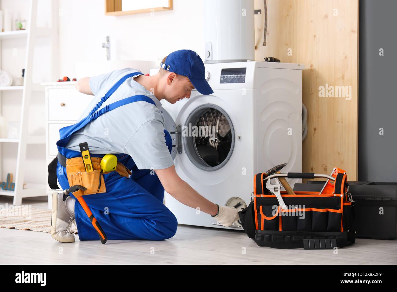 Technicien masculin réparant la machine à laver dans la salle de bain Banque D'Images