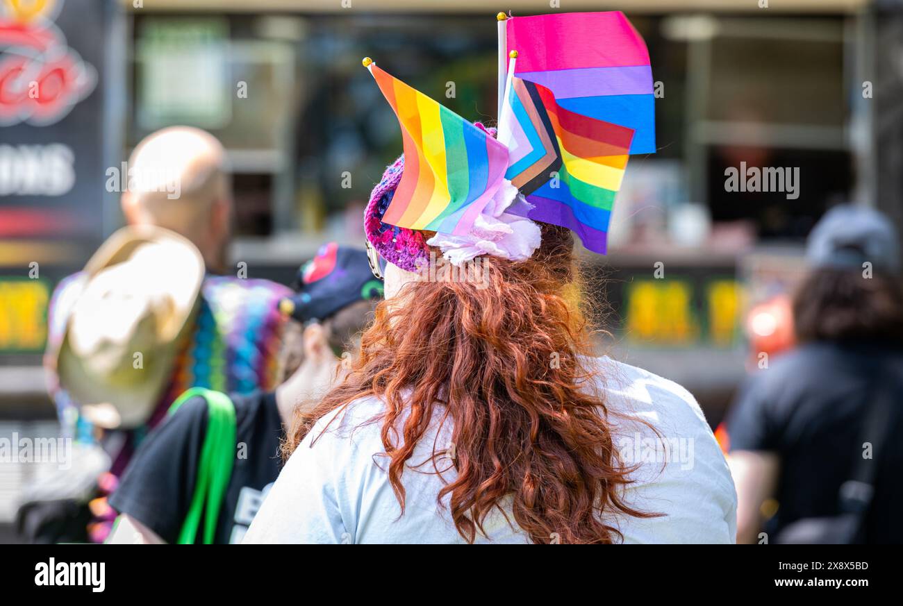 L'arrière de la tête d'une femme avec arc-en-ciel, fierté du progrès et drapeaux bisexuels à la 2024 placer Pride. Banque D'Images