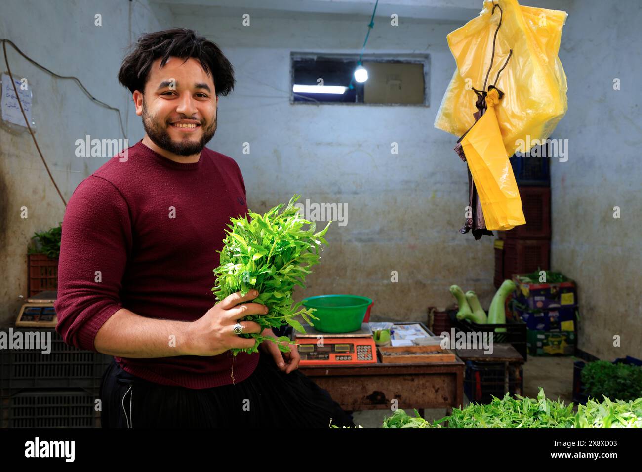 Un vendeur de légumes tenant un tas de feuilles de menthe souriant à la caméra dans le marché de Ghardaia. Vallée de Mzab. Province de Ghardaia. Sahara du Nord. Algérie Banque D'Images