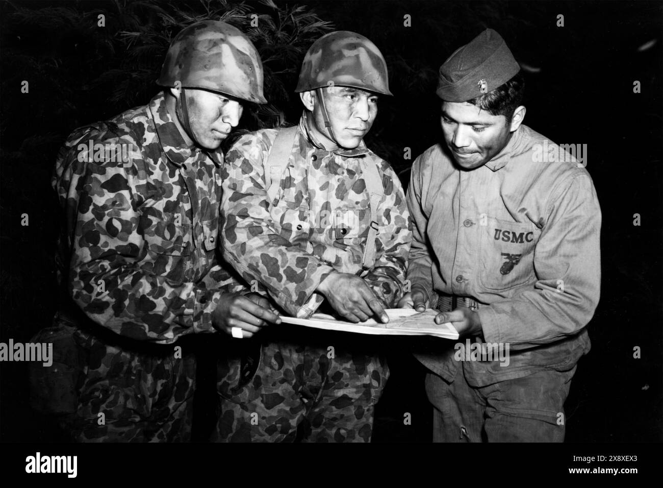 Les locuteurs de code Navajo, membres de la compagnie de signaux et rattachés à la 1re Division des Marines dans le Pacifique Sud-Ouest, étudient un problème nocturne à l'école scoute amphibie menée par la section du renseignement pendant la seconde Guerre mondiale en 1943. Banque D'Images