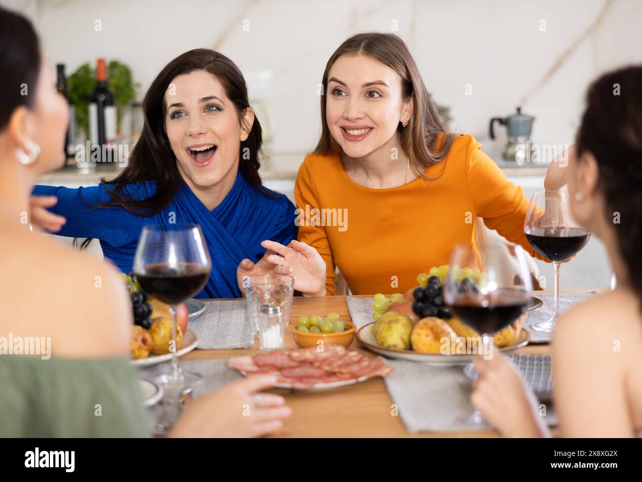 Des femmes heureuses se sont rassemblées autour d'une table festive ; participant à des discussions animées et appréciant les délices du vin Banque D'Images