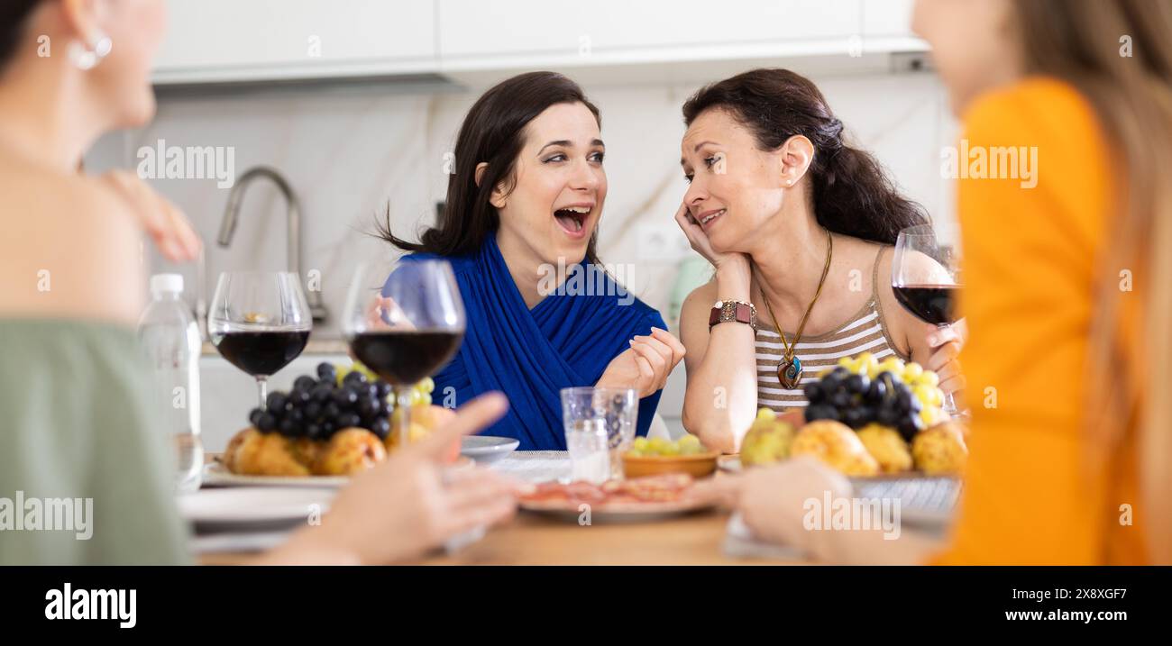 Des femmes heureuses se sont rassemblées autour d'une table festive ; participant à des discussions animées et appréciant les délices du vin Banque D'Images