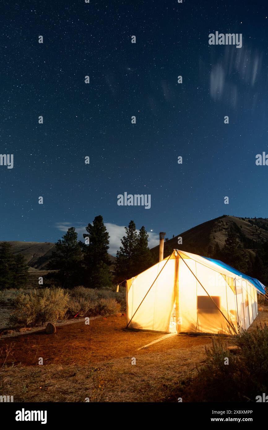 Tente chaude dans le camp de chasse incandescent sous le ciel étoilé de nuit, Thomas Creek, Frank Church River of No Return Wilderness, Idaho, États-Unis Banque D'Images
