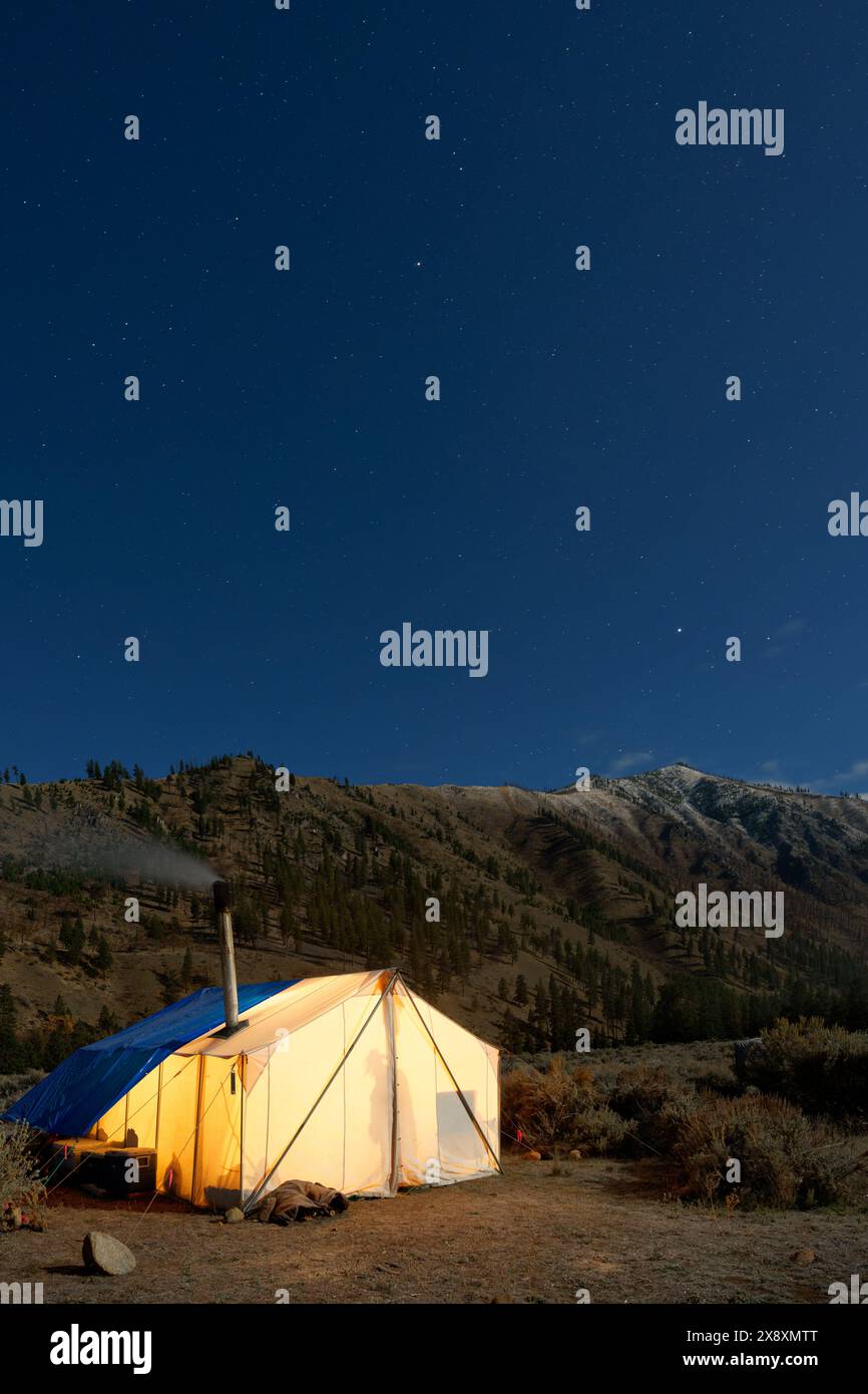 Tente chaude dans le camp de chasse incandescent sous le ciel étoilé de nuit, Thomas Creek, Frank Church River of No Return Wilderness, Idaho, États-Unis Banque D'Images
