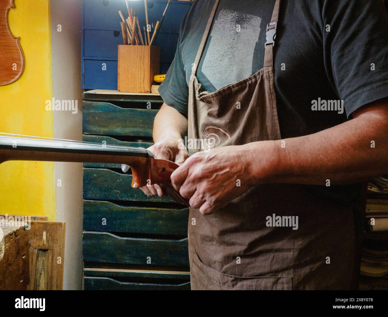 Gros plan d'un artisan qualifié réparant soigneusement le cou d'une guitare dans un atelier de menuiserie coloré et wellequipped Banque D'Images