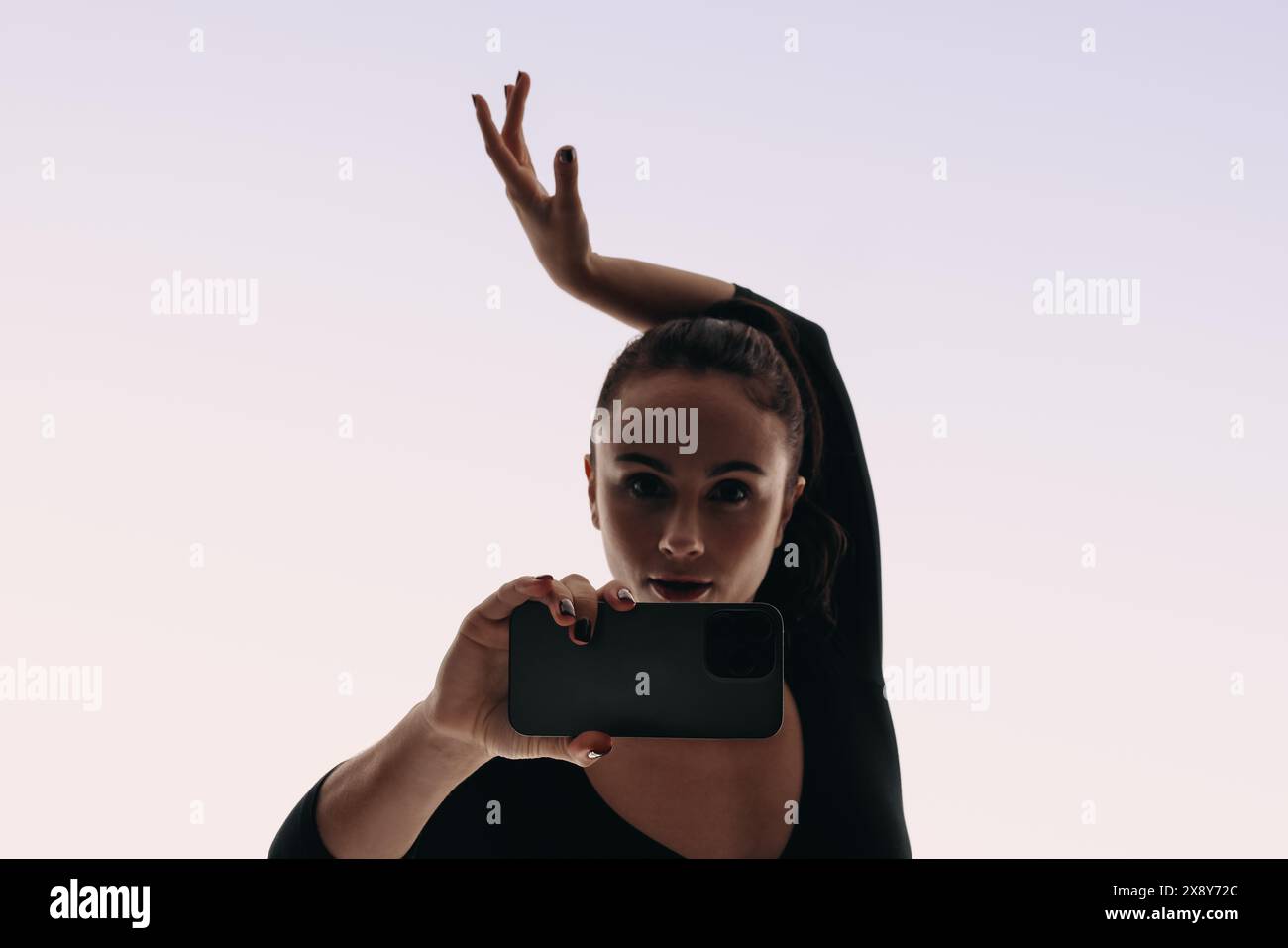 Interprète confiante enregistrant une vidéo selfie de sa routine de danse avec un smartphone. Avec des mouvements de danse expressifs, elle capture son style unique Banque D'Images