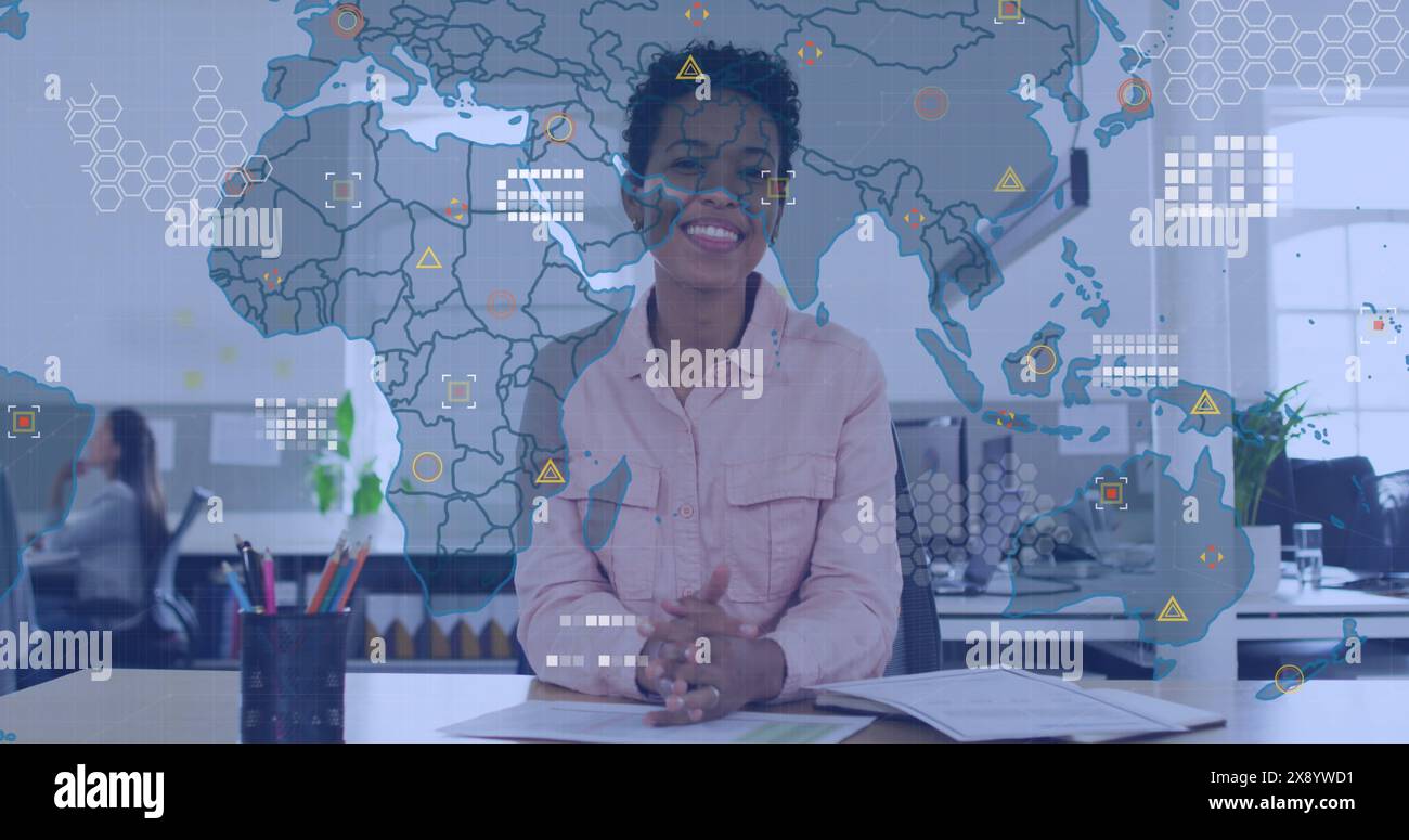 Image de la carte du monde au-dessus d'une femme afro-américaine agitant et souriant regardant la caméra au bureau Banque D'Images