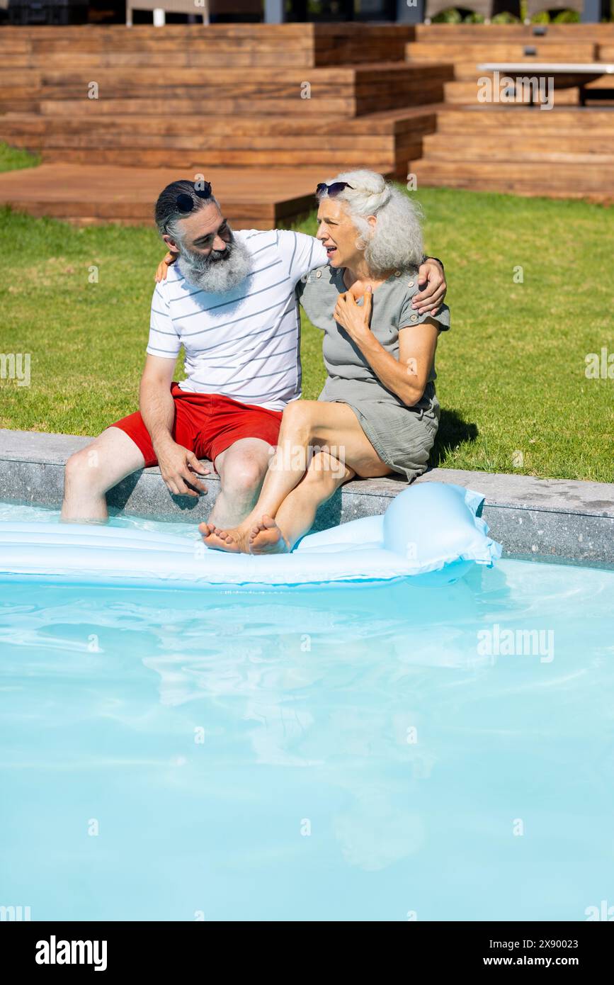 À l'extérieur, des amis seniors caucasiens rient ensemble au bord de la piscine Banque D'Images