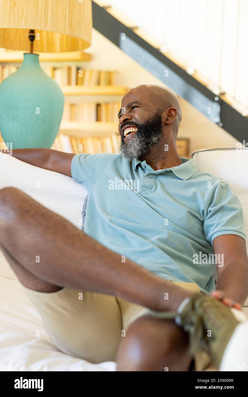 À la maison, un homme afro-américain senior riant sur le canapé Banque D'Images