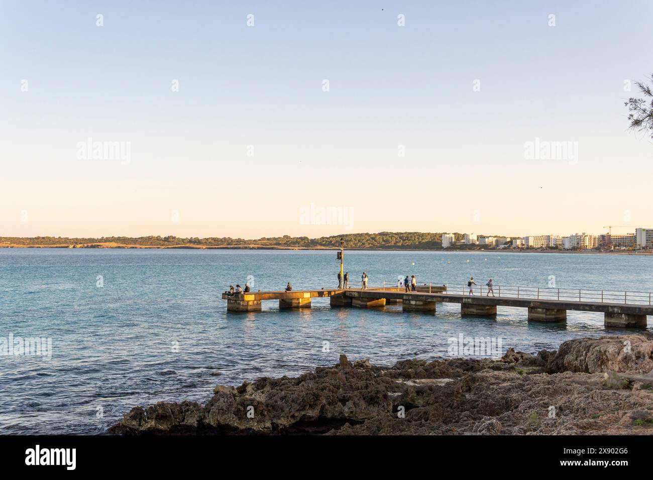 Cala Millor, Espagne ; 13 avril 2024 : vue générale de la vieille jetée avec les touristes, dans la station touristique majorquine de Cala Millor au coucher du soleil Banque D'Images