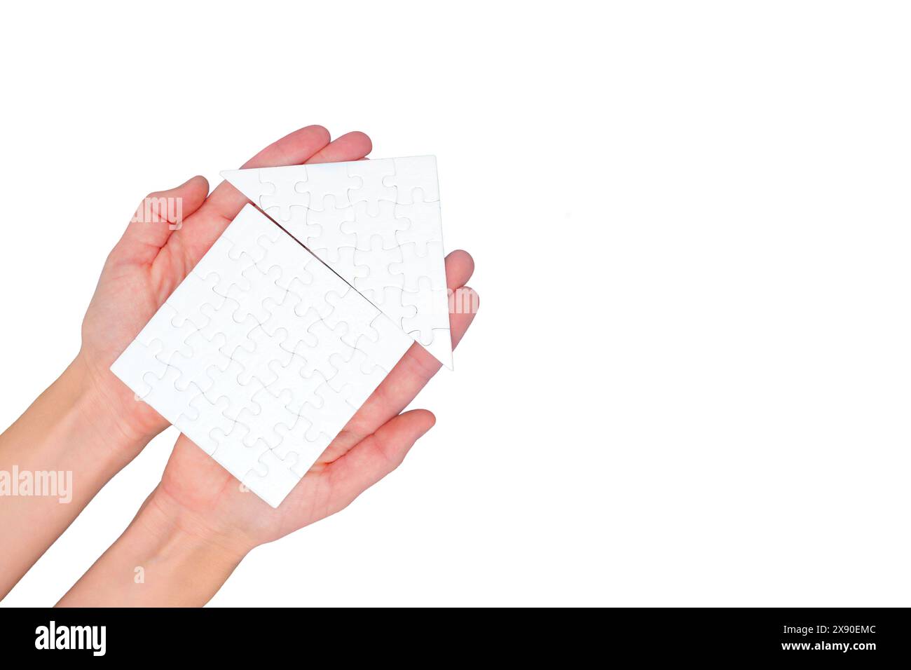 Maison de puzzle vierge artisanale tenue sur un fond blanc immaculé. Banque D'Images