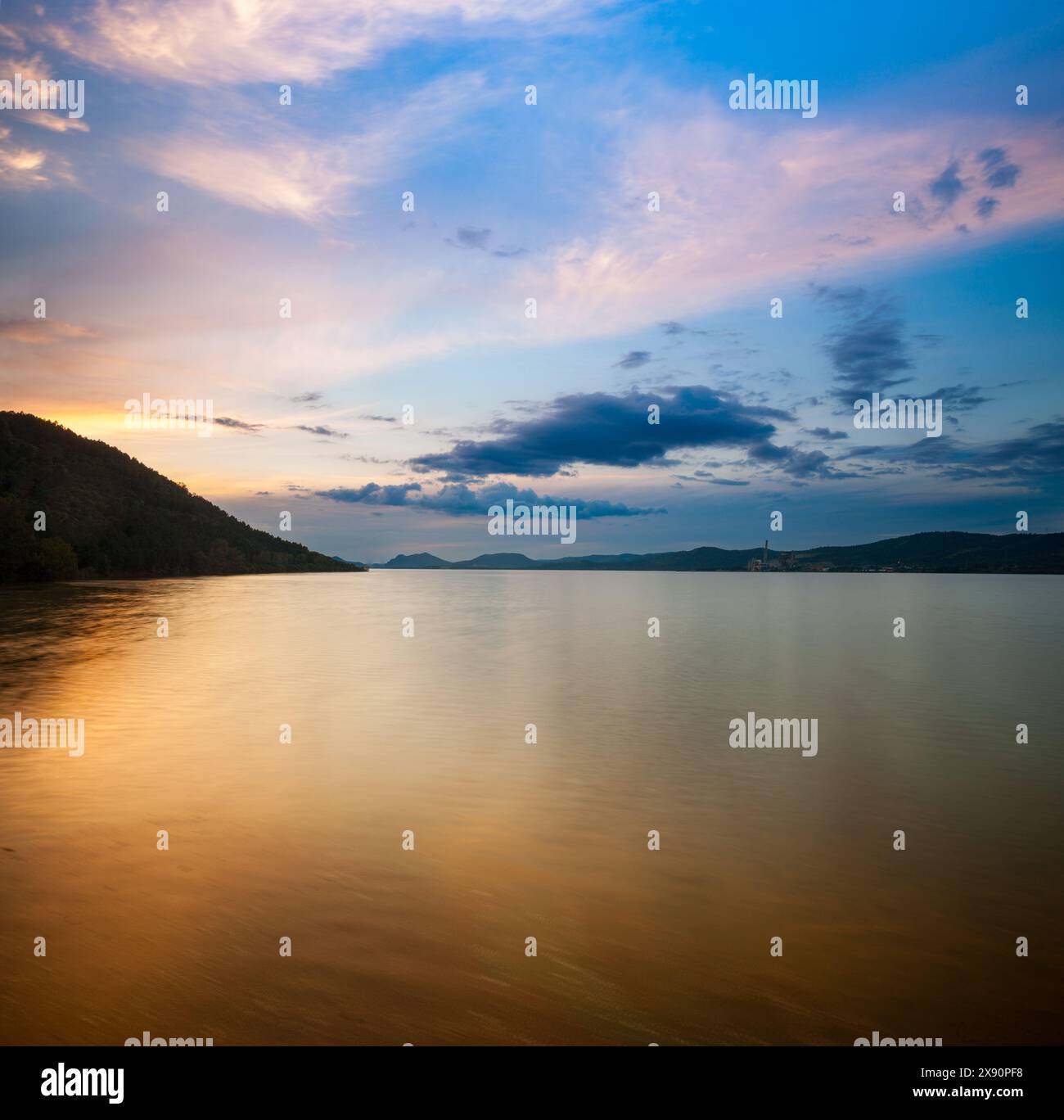 Une scène nocturne tranquille sur Embalse de Puente Nuevo reflétant un ciel bleu éclatant et des montagnes silhouettes. Banque D'Images