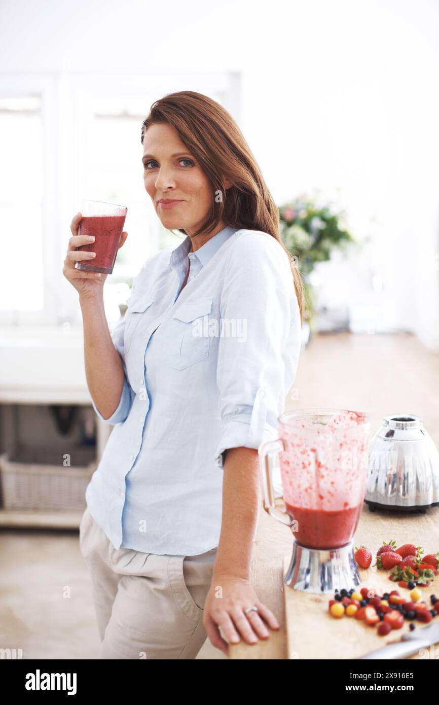 Femme, portrait et boisson dans la cuisine pour smoothie ou shake, recette artisanale et fraîche pour le petit déjeuner détox. Fille, fraise et idées de repas Banque D'Images