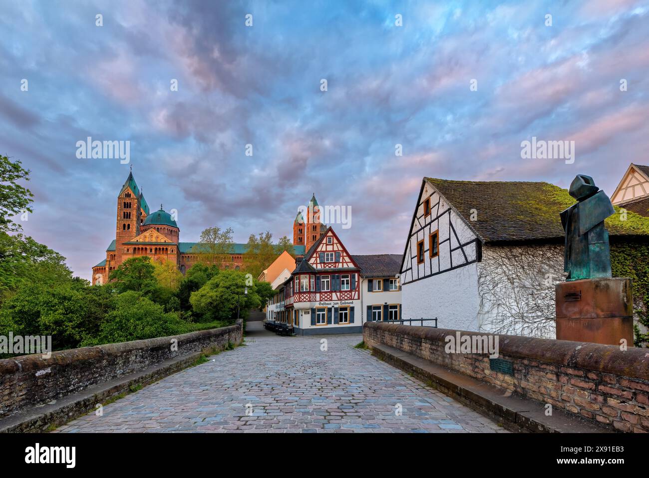 Fachwerkhaeuser und eine Statue auf einer Bruecke mit Blick auf eine Kirche im Abendhimmel, die eine friedliche historische Atmosphaere bietet Banque D'Images