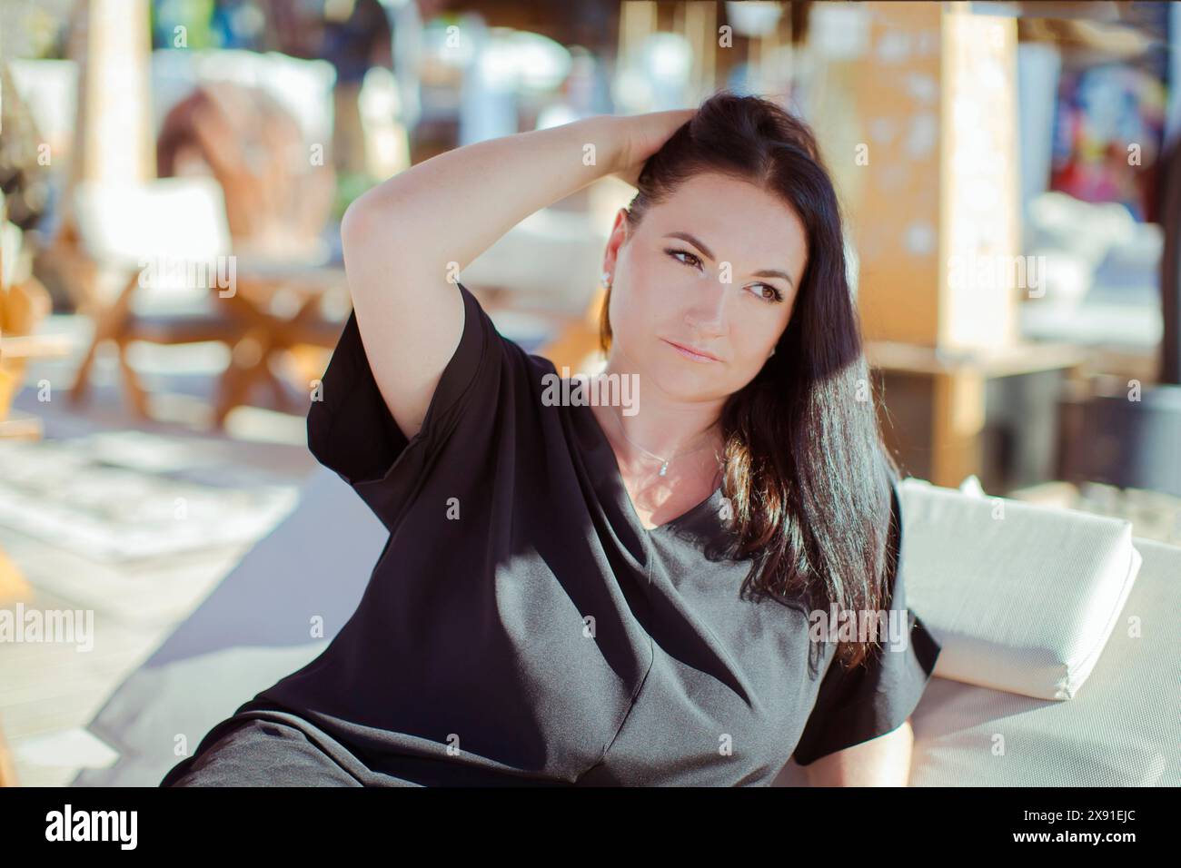 Une femme dans une robe noire se relaxant à l'extérieur par une journée ensoleillée. Turquie, Antalya Banque D'Images