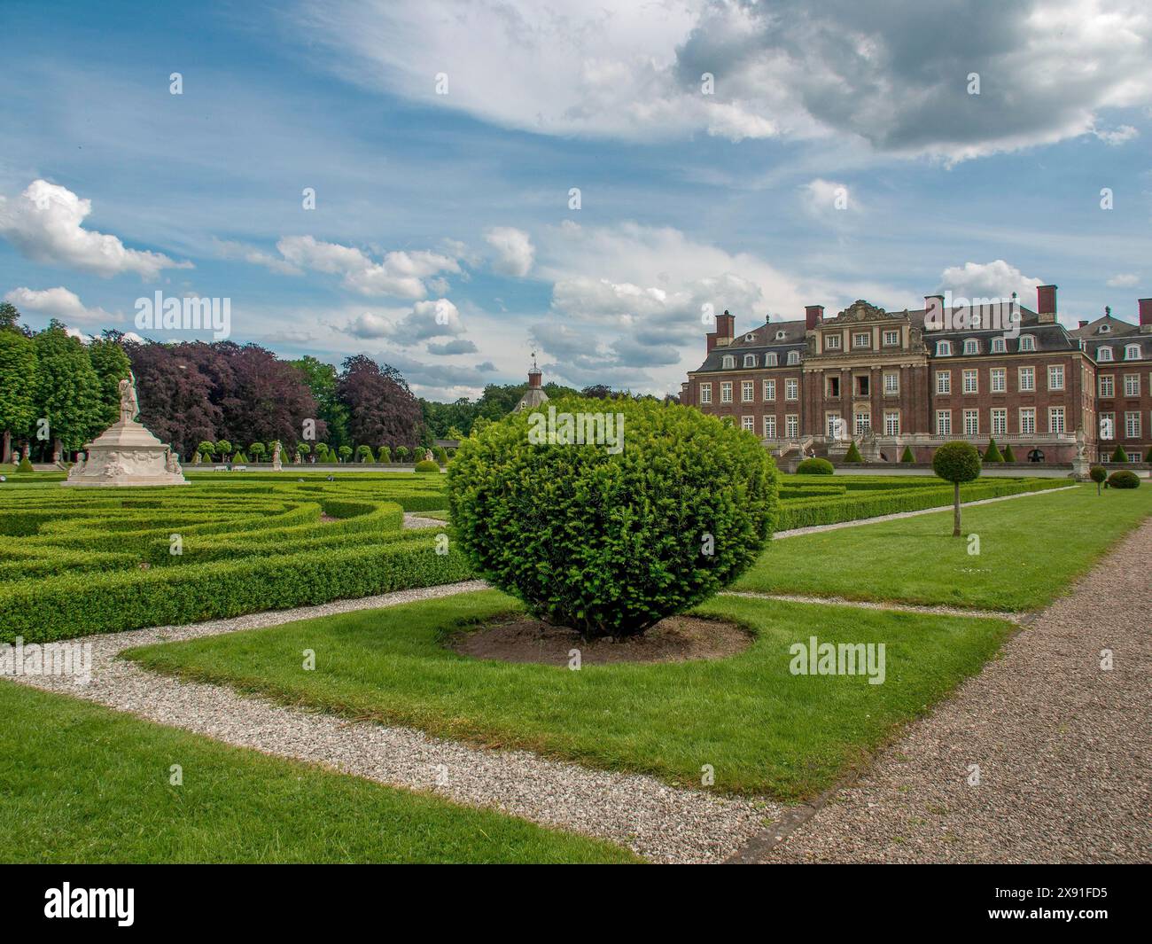 Jardin symétrique avec des haies bien entretenues et des chemins en face d'un château historique sous un ciel nuageux, château historique avec un parc verdoyant avec Banque D'Images