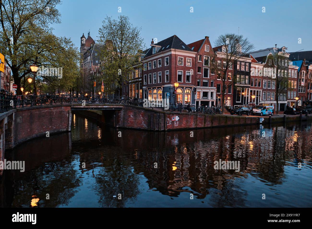 Pays-Bas, Amsterdam - 10 avril 2024 : maisons de canal d'Amsterdam, vélos et pont dans le quartier Jordaan au crépuscule Banque D'Images