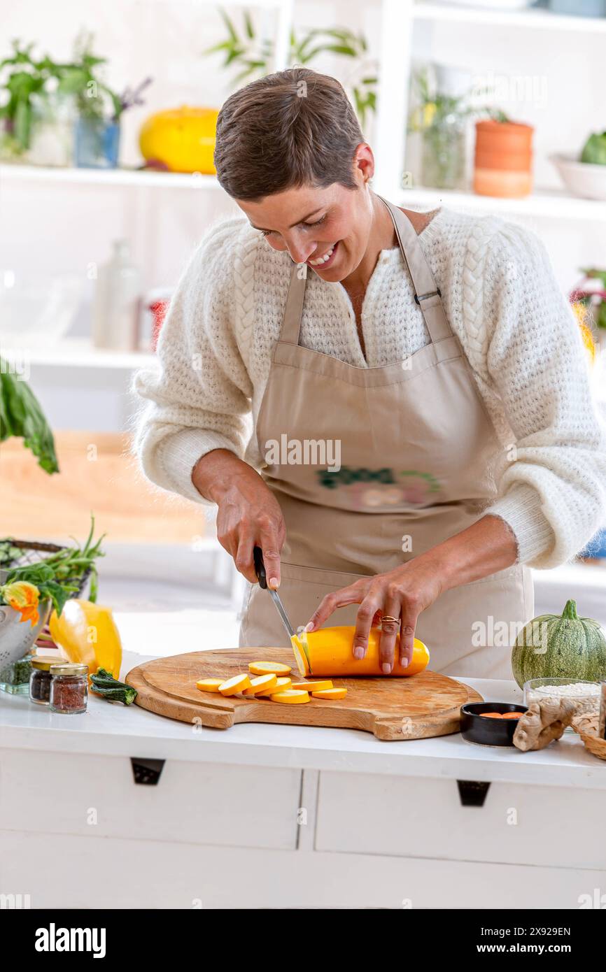 Jeune femme coupant une courgette jaune recettes végétariennes - santé 016643 071 Banque D'Images