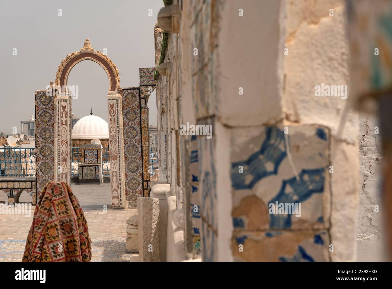 Une vue sur le toit d'un bâtiment en forme de dôme à travers une arche décorée de motifs traditionnels en mosaïque, une partie du quartier de la médina désigné par l'UNESCO de la capitale tunisienne, Tunisie, Afrique du Nord. Banque D'Images