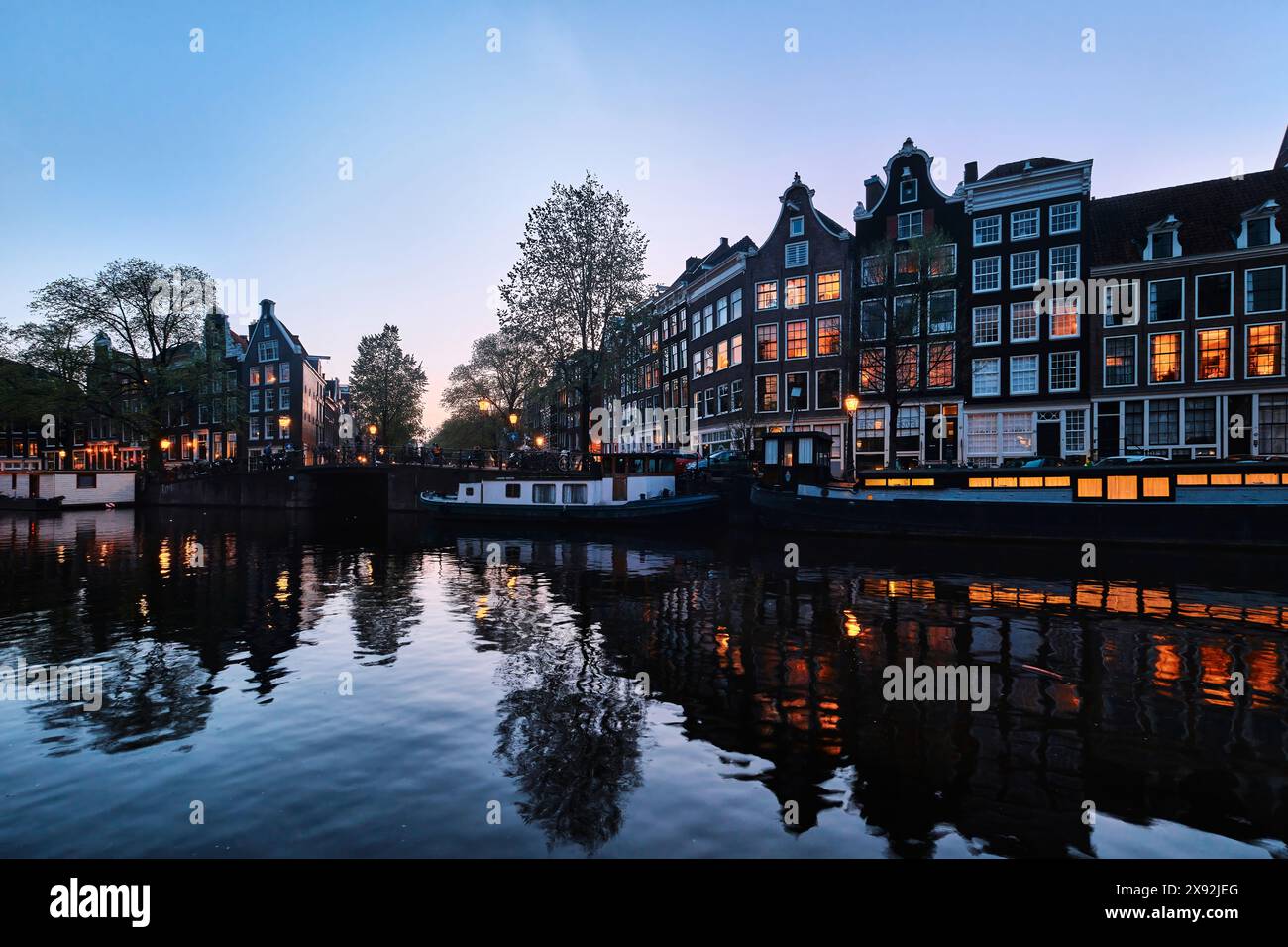 Pays-Bas, Amsterdam - 10 avril 2024 : maisons de canal d'Amsterdam, vélos et pont dans le quartier Jordaan au crépuscule Banque D'Images