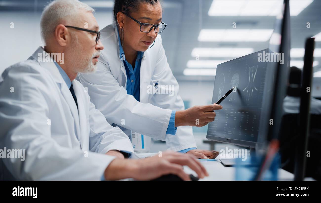 Hôpital médical : le neurologue et le neurochirurgien parlent, utilisent l'ordinateur, analysent l'IRM du patient, diagnostiquent le cerveau. Laboratoire de clinique de santé : deux médecins professionnels regardent la tomodensitométrie. Gros plan Portrait Banque D'Images