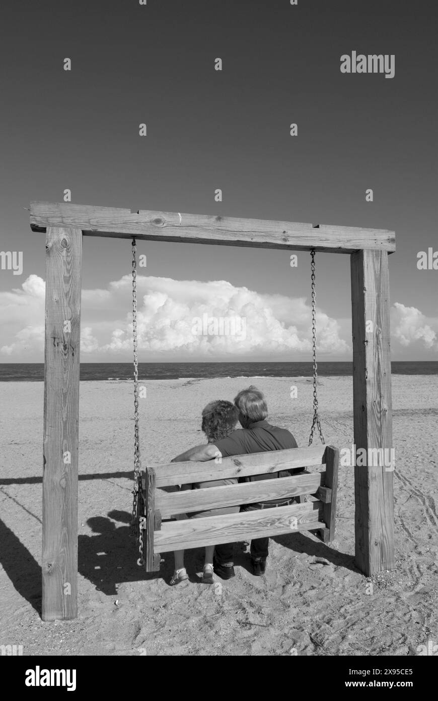 Un couple d'âge moyen se balançant sur une balançoire en bois à la plage de Tybee Island, Géorgie, États-Unis. Banque D'Images