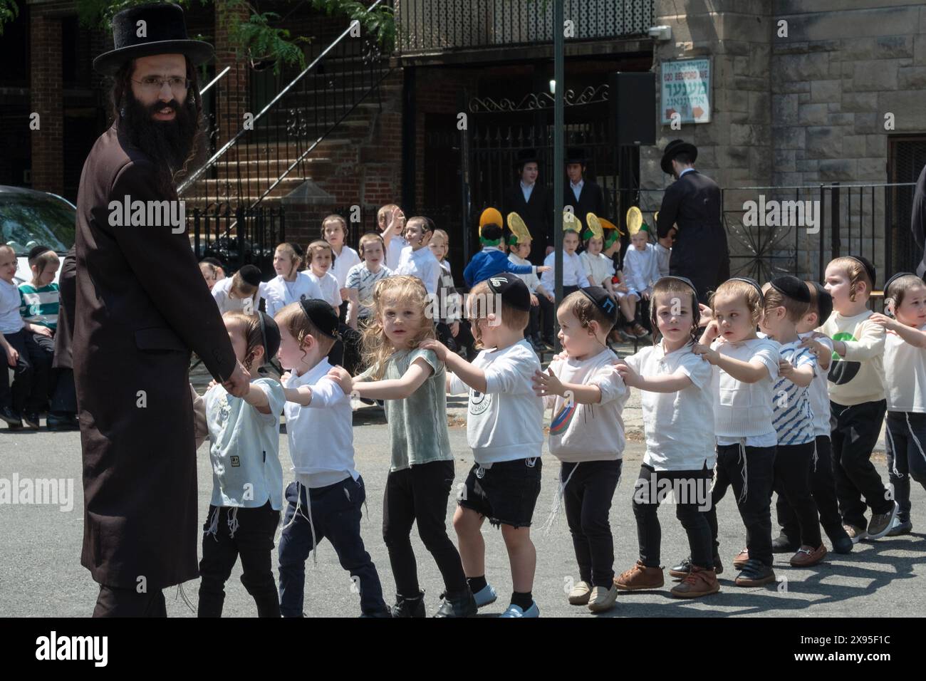 Un rabbin et ses jeunes garçons marchent en formation tout en célébrant Lag B'Omer 2024. À Brooklyn, New York. Banque D'Images