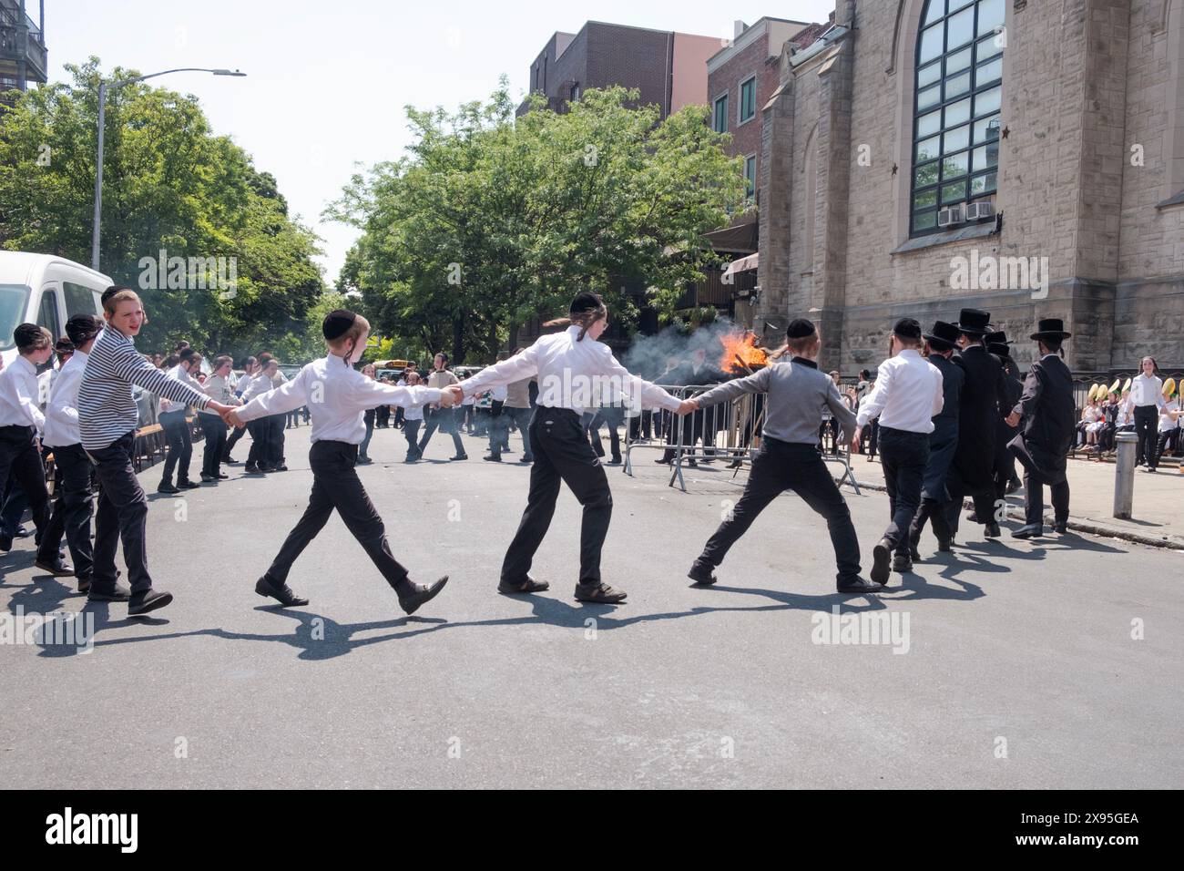 Les étudiants et enseignants juifs orthodoxes célèbrent Lag B'Omer en dansant près d'un feu traditionnel. Dans une rue fermée à Brooklyn, New York. Banque D'Images