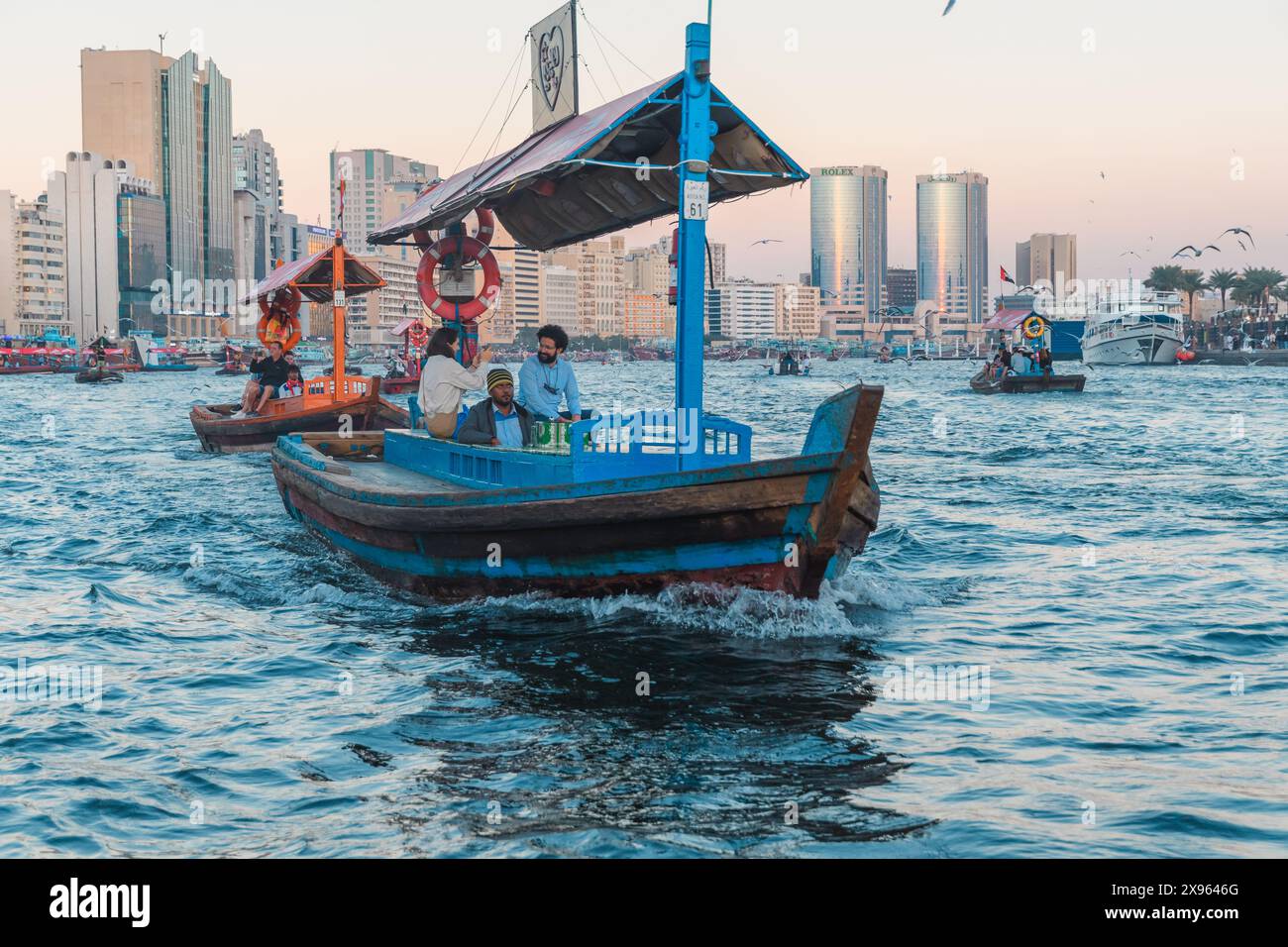 Dubaï, Émirats arabes Unis - 6 janvier 2024 : un bateau abra traditionnel navigue sur fond de toits modernes de Dubaï, soulignant la dualité culturelle de la ville. Banque D'Images