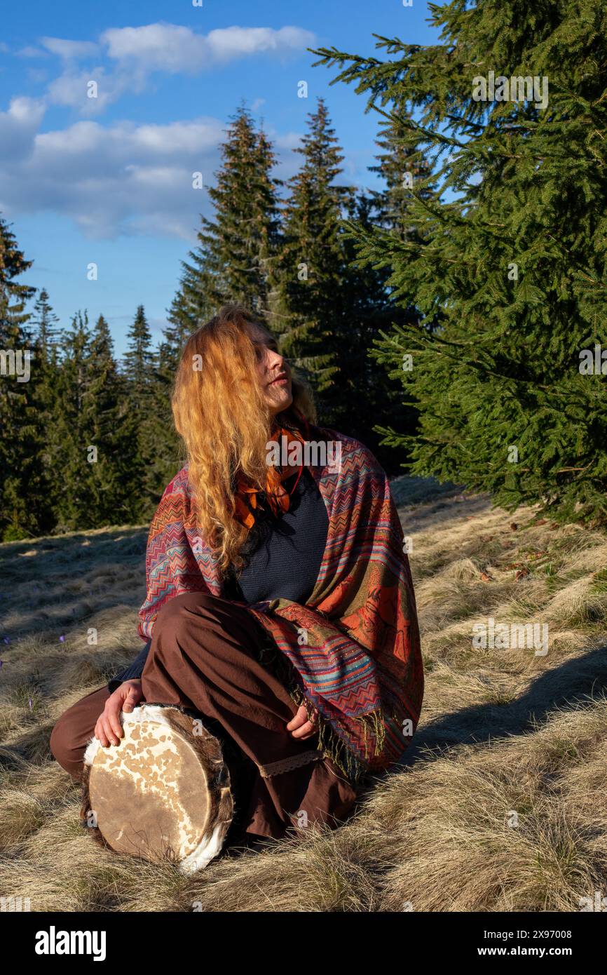 Belle fille chamanique jouant sur le tambour de cadre de chaman dans la nature. Photo de haute qualité Banque D'Images