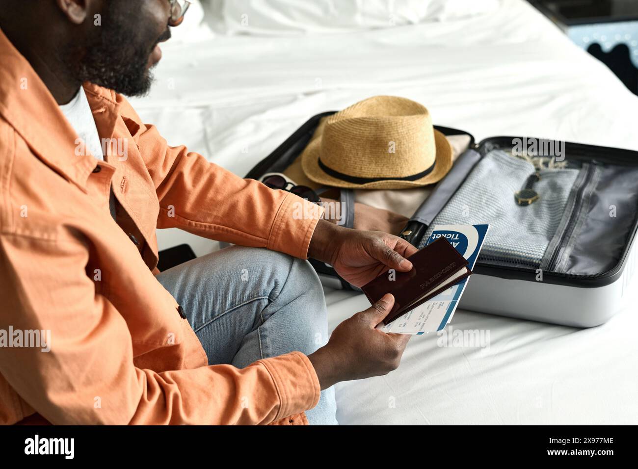 Gros plan à angle élevé de l'homme afro-américain emballant le passeport et les documents dans la valise et se préparant pour l'espace de copie de voyage Banque D'Images