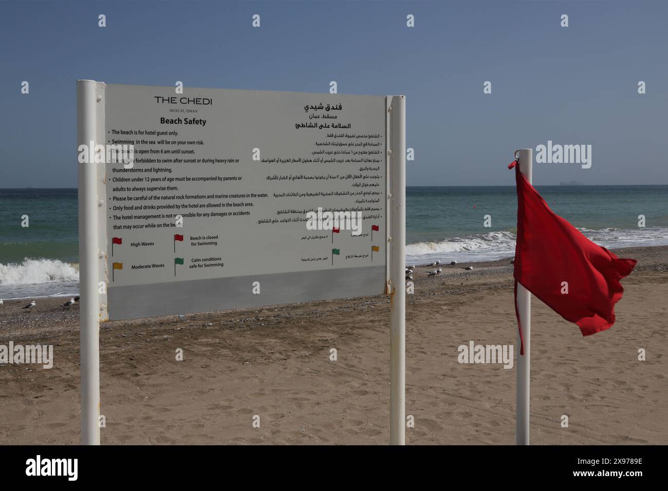 Drapeau rouge avertissement de hautes vagues ou plage fermée et panneau d'information sur la plage au Chedi Hotel Muscat Oman Banque D'Images