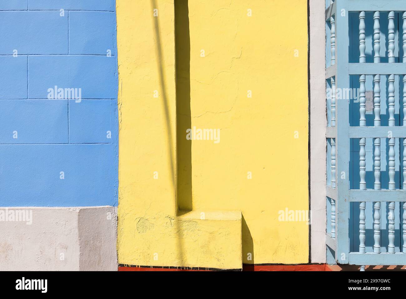330 mur coloriste de la maison coloniale montrant la fenêtre habituelle, à volets en bois, en forme de porte, sur la façade bleu-jaune-rouge-blanc. Sancti Spiritus-Cuba. Banque D'Images