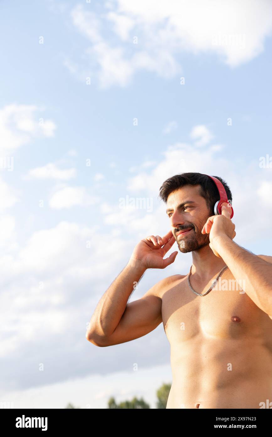 Homme athlète écoutant de la musique avec des écouteurs. homme faisant du sport dehors écoutant de la musique Banque D'Images
