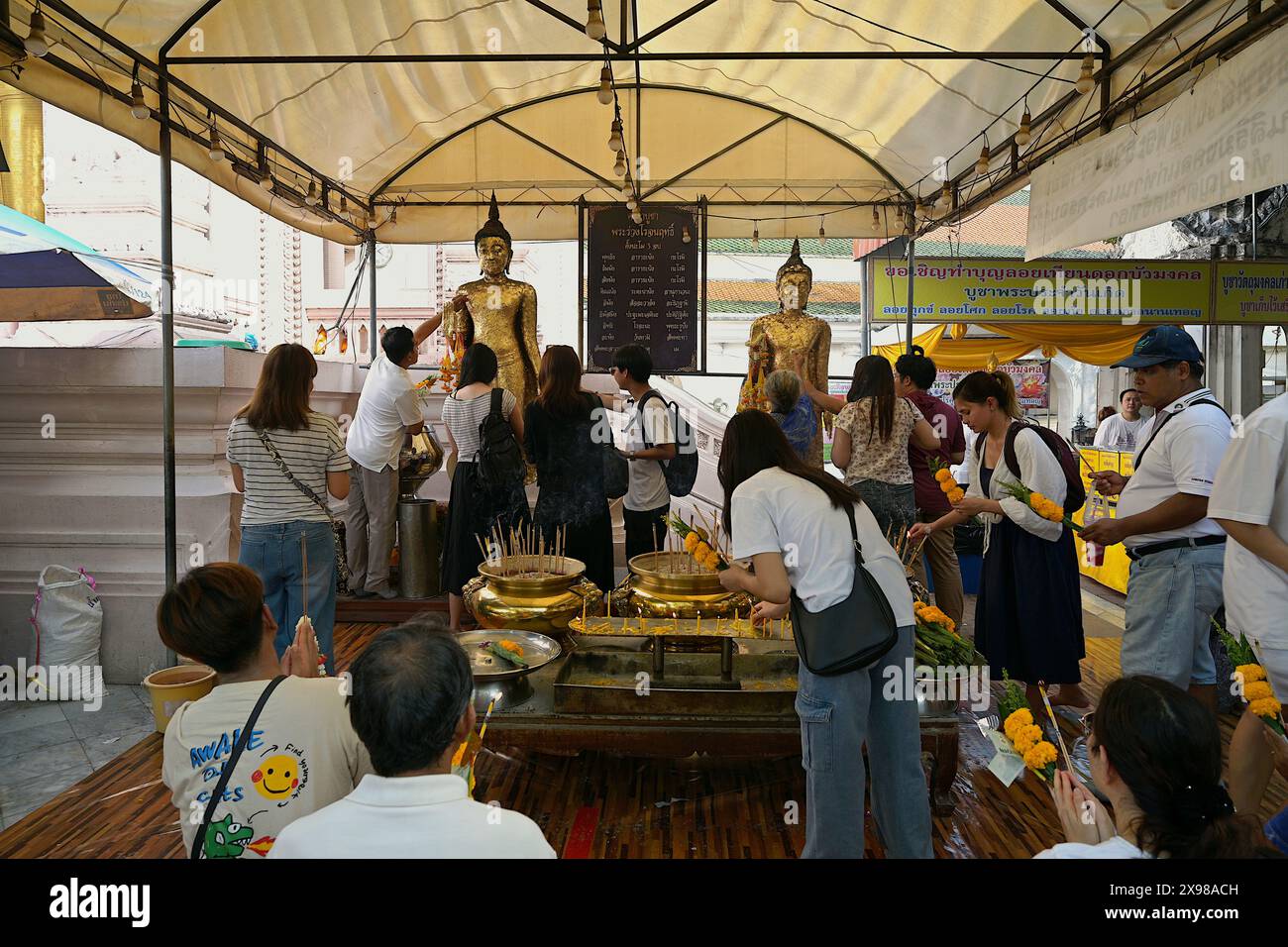 Les gens font du mérite et appliquent des feuilles d'or sur les images de Bouddha, Vesak Day 2024, au Wat Phra Pathommachedi Ratcha Wora Maha Wihan, Nakhon Pathom, Thaïlande Banque D'Images