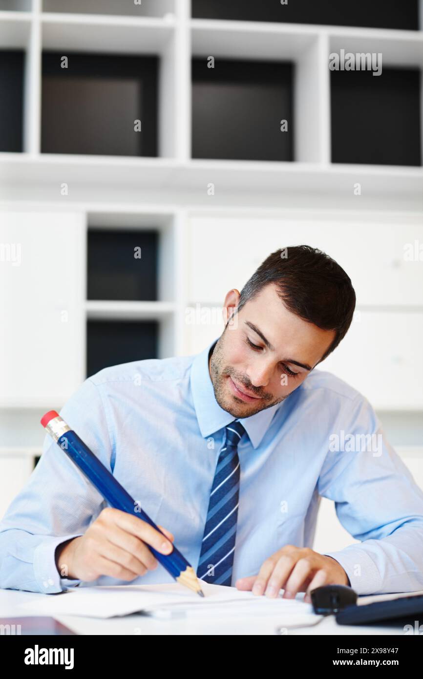 Sourire, bureau et homme d'affaires avec grand crayon dans le bureau pour la planification d'entreprise, la finance et l'idée. Heureux, l'homme et l'écriture sur papier au lieu de travail pour Banque D'Images