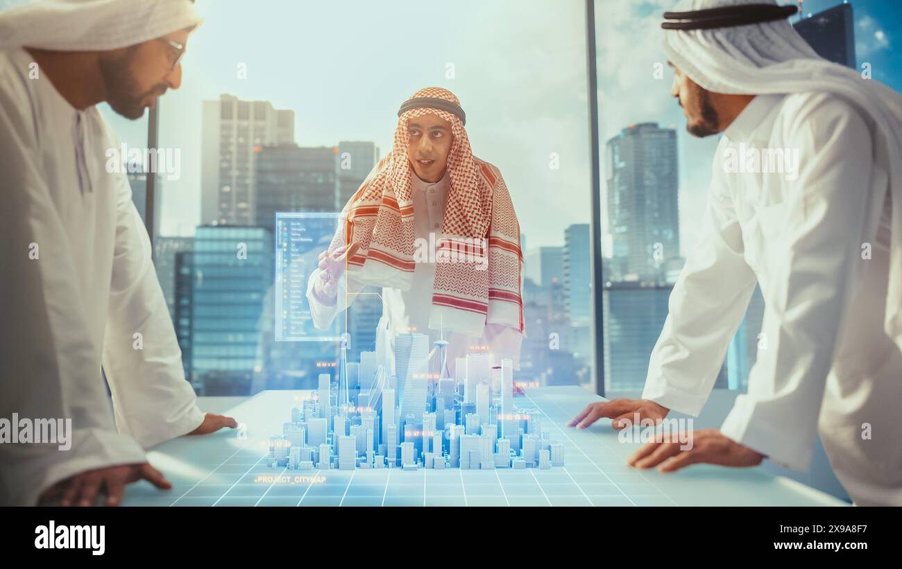 Groupe de développeurs d'affaires immobilières musulmanes en vêtements traditionnels discutent des opportunités d'investissement basées sur le modèle de ville 3D de réalité augmentée holographique dans leur bureau moderne dans un gratte-ciel. Banque D'Images