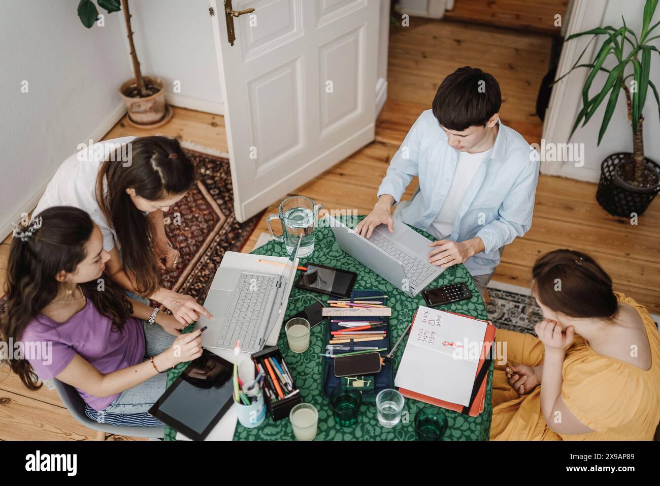 Vue en angle élevé de la mère des enfants scolarisant à la maison à l'aide d'un ordinateur portable sur la table à la maison Banque D'Images