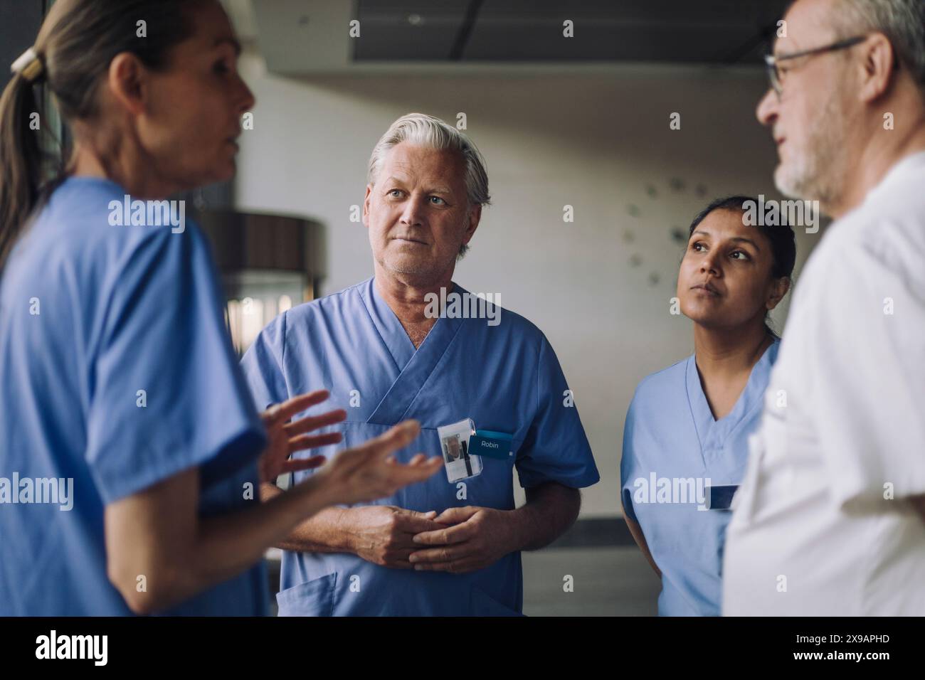 Heureux médecins hommes et femmes dans les gommages médicaux discutant à l'hôpital Banque D'Images