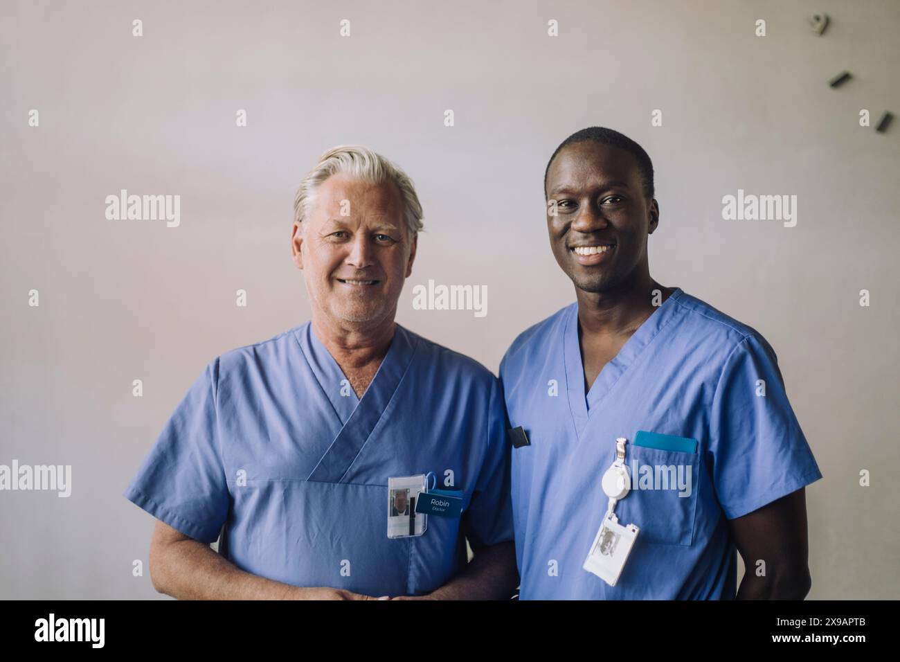 Portrait de médecins multiraciaux souriants debout devant un mur à l'hôpital Banque D'Images