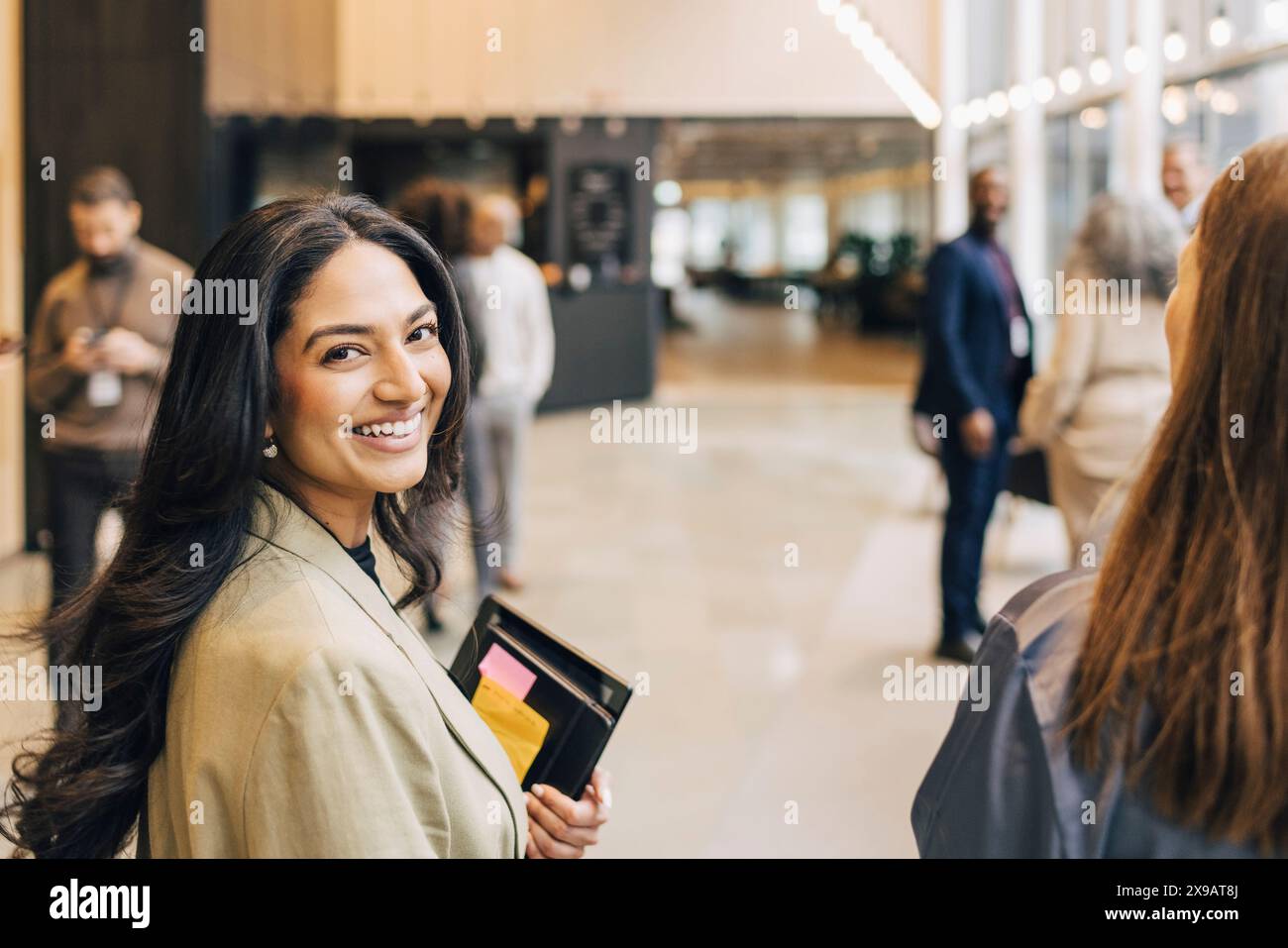 Vue latérale d'une jeune femme entrepreneure souriante avec de longs cheveux au centre de congrès Banque D'Images