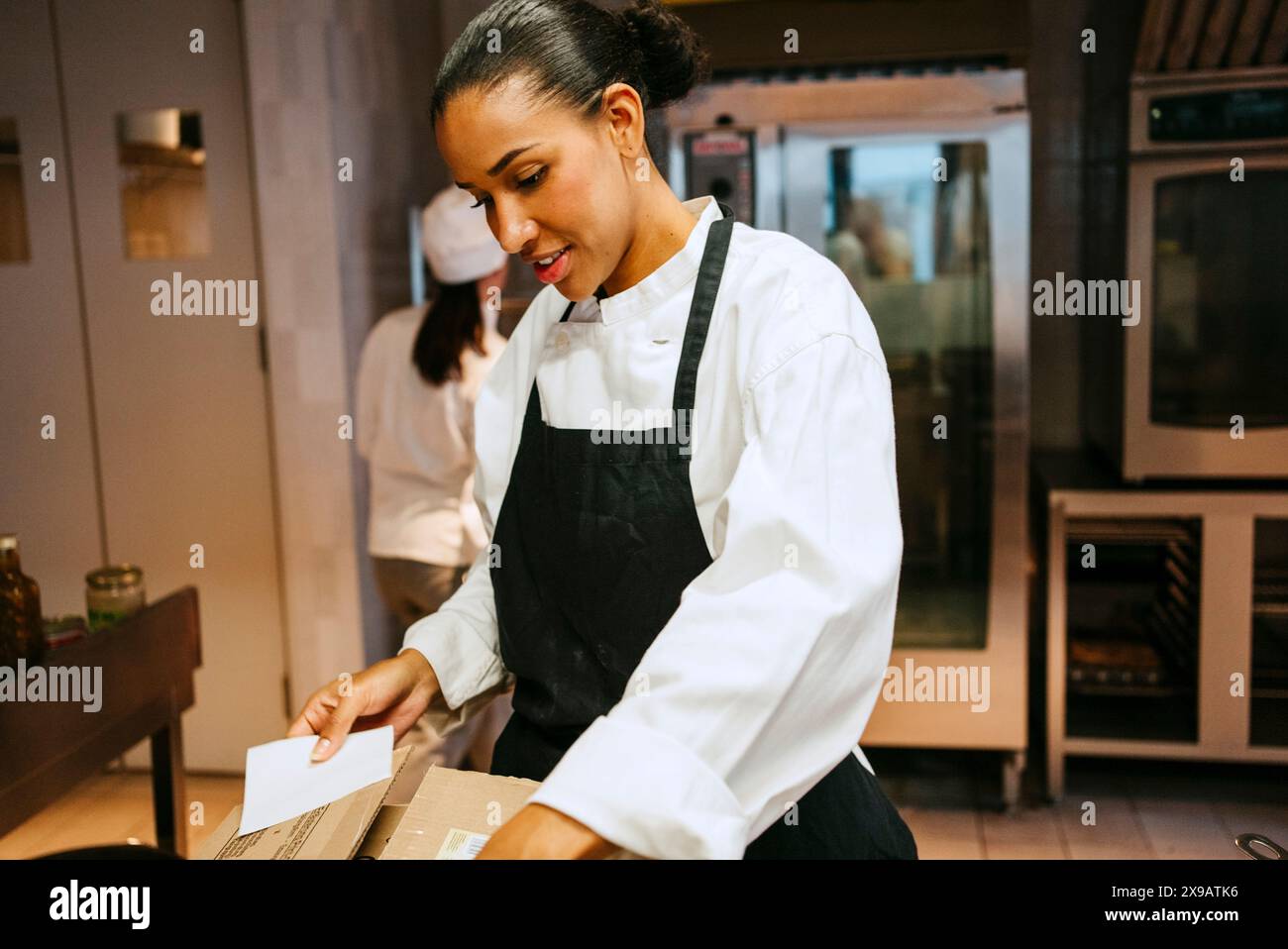 Jeune femme chef vérifiant l'inventaire tout en se tenant debout dans la cuisine commerciale Banque D'Images