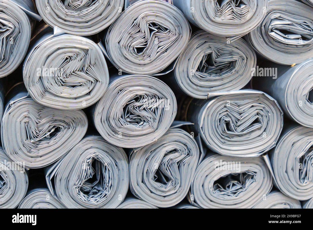 Rouleaux de plastique gris empilés de manière désordonnée, créant un bruit de papier rouleau Banque D'Images