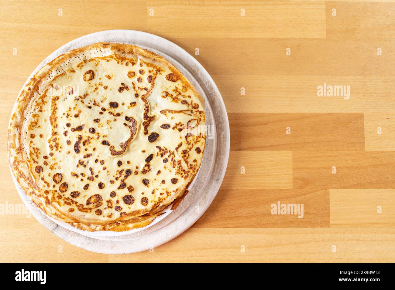 Photographie de nourriture de table d'une assiette blanche de fines crêpes se tient sur le côté sur une table en bois de hêtre Banque D'Images